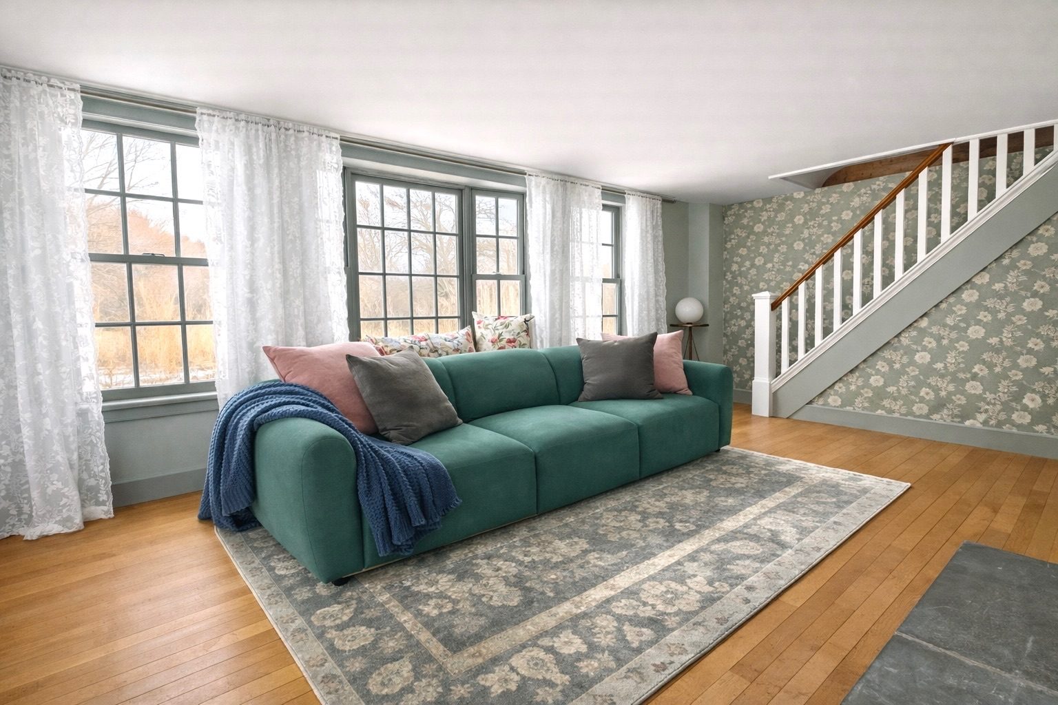 Sunlit living room with floral wallpapered staircase